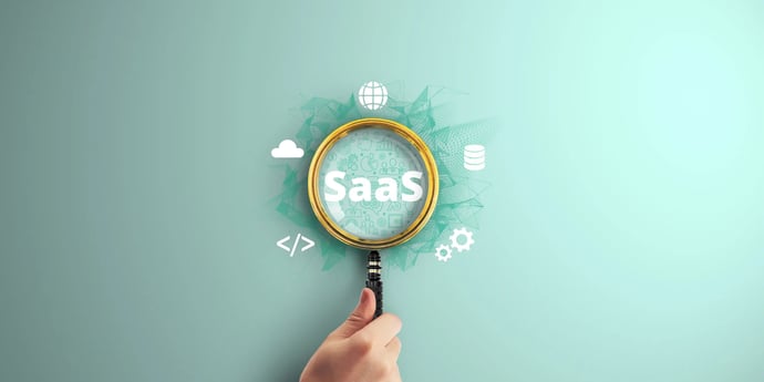 An abstract image shows a hand with a magnifying glass, over the word 'SaaS' against a green background. Cogs & cloud symbols are around the glass.
