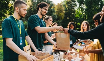 Volunteers at an outdoor food bank handing out supplies, illustrating health and safety in charities and voluntary organisations.