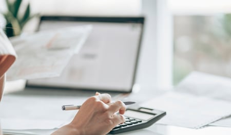 Woman using a calculator to work out redundancy pay entitlement while preparing for the process of making staff redundant.