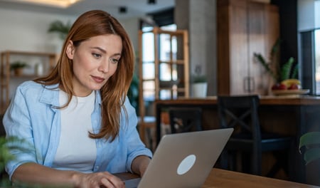 Employee working at a laptop in a home, illustrating work from home health and safety considerations