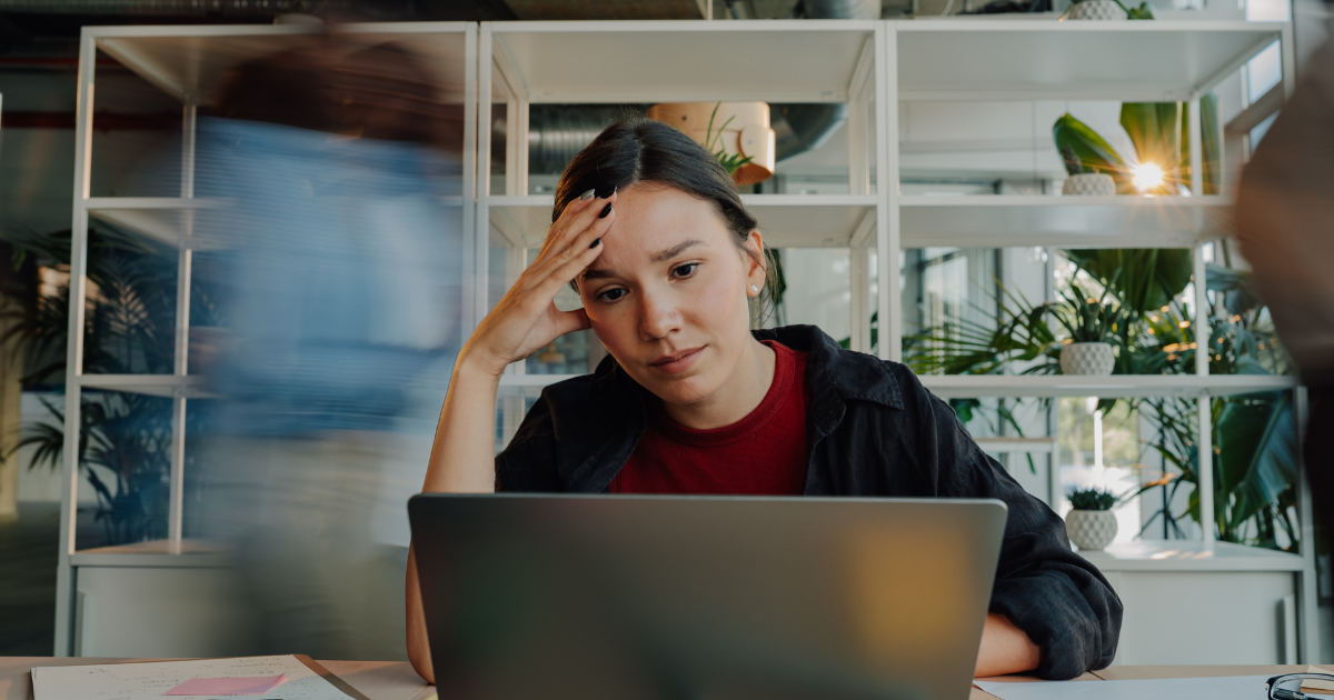 Office worker sitting at a desk with their head in their hands, illustrating stress and burnout at work.