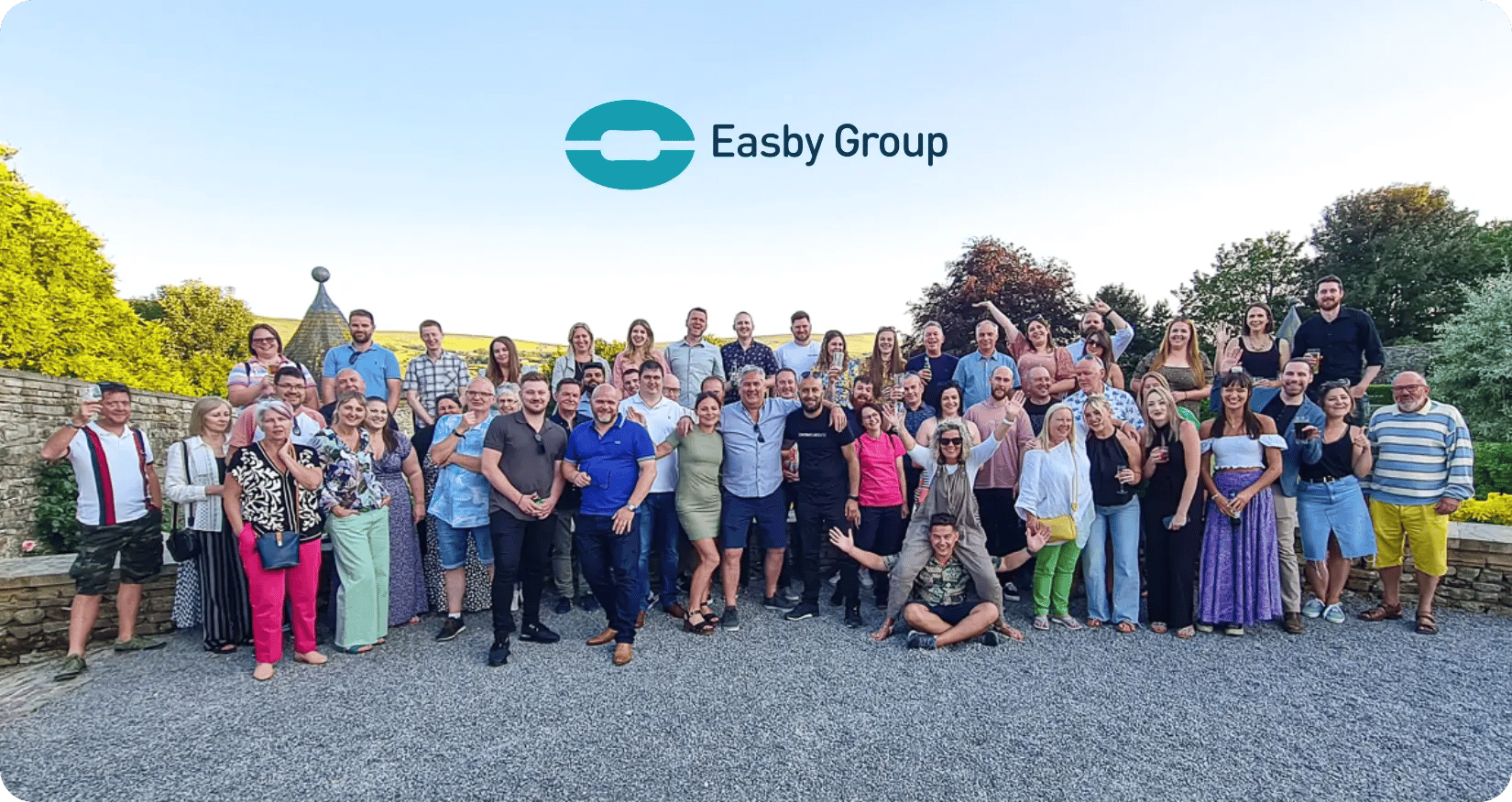 Easby Group whole team photo outside at a summer party with their logo above them in the sky