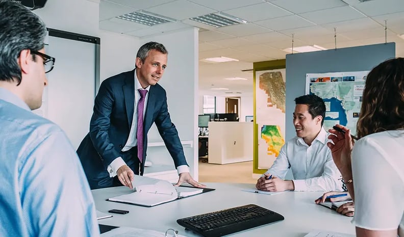 Executive talking to 3 employees over a desk