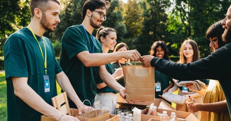 Volunteers at an outdoor food bank handing out supplies, illustrating health and safety in charities and voluntary organisations.