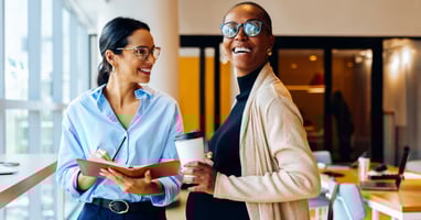 Two colleagues talking in an office, illustrating the importance of maternity risk assessments in supporting pregnant employees at work.