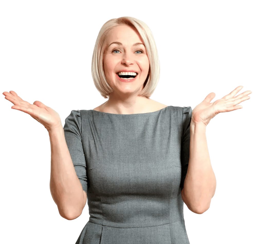 lady with short blonde hair in a smart grey dress smiling, looking happily at the camera with her hands in a shrug position