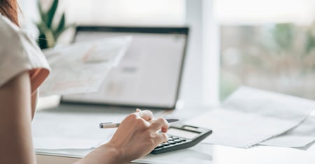 Woman using a calculator to work out redundancy pay entitlement while preparing for the process of making staff redundant.