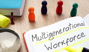 A notepad reading 'Multigeneration Workforce', with small people shaped objects sat beside the notepad. 