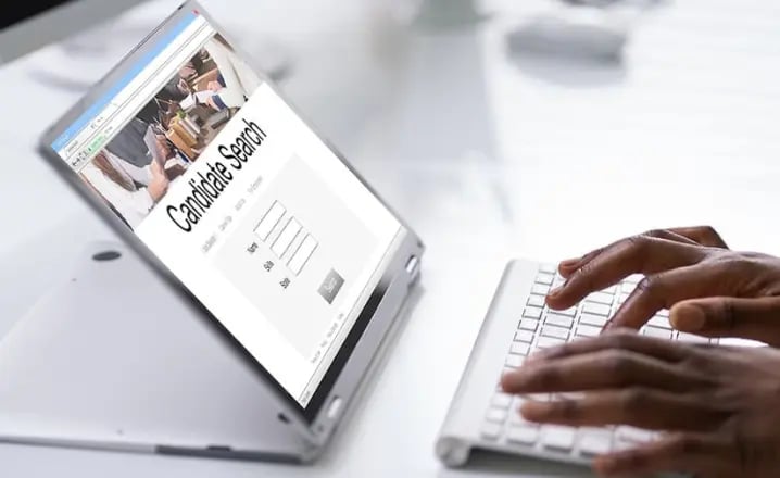 Someone types on a keyboard, where 'candidate search' is shown on their screen