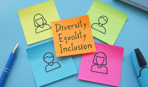 Colourful post-it notes are shown on a desk. The central one reads, 'diversity, equality, inclusion