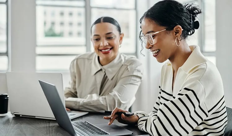 Two women smile in a one-to-one meeting in an office