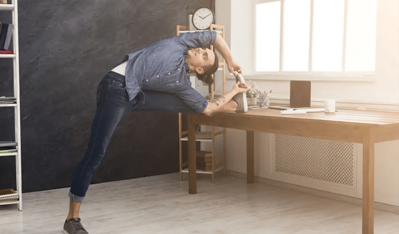 man streching leg against a desk