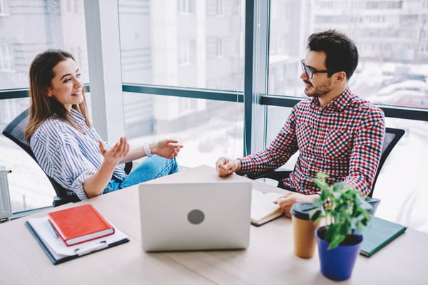 millennial employees desk worker laptop talking office