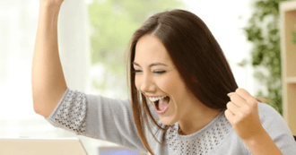 A woman is celebrating success in her personal development. She is punching a fist in the air and cheering.