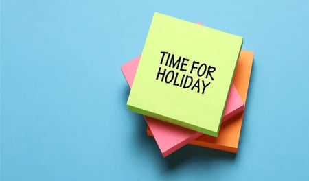 A stack of colourful sticky notes. "Time for a holiday" has been written on the top sticky note.
