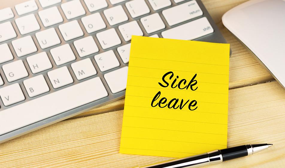 A keyboard and mouse are shown. A yellow sticky note on the keyboard reads 'sick leave' with a pen next to it. 