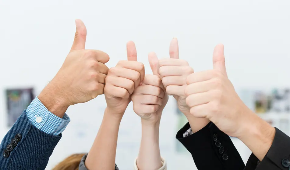 Five colleagues are in an office and holding their thumbs up.
