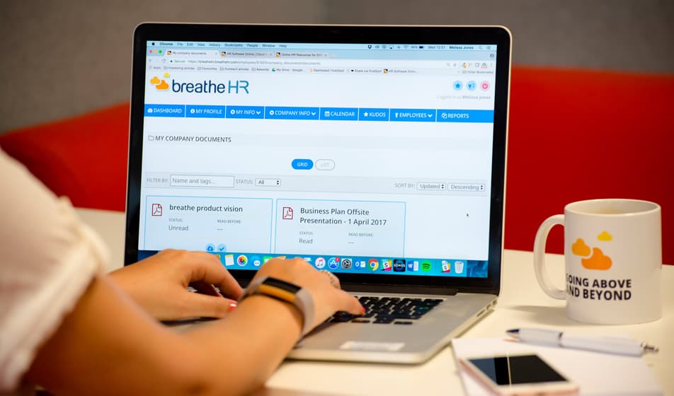 An image of a laptop on a desk sat next to a Breathe branded mug. The laptop is showing the Breathe dashboard.