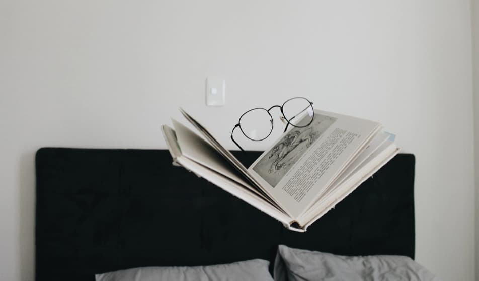 Glasses and newspaper hovering above a bed