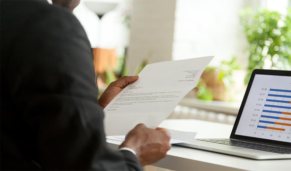 Man dressed in a suit reading a letter at his desk