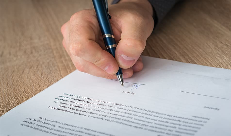 Man signing paperwork with a ballpoint pen