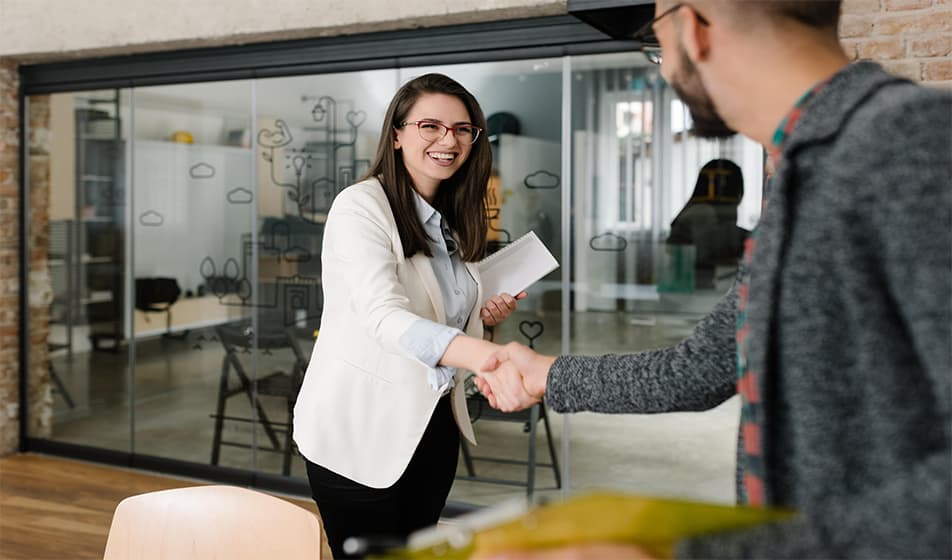 Woman wearing a white jacket shaking a mans hand