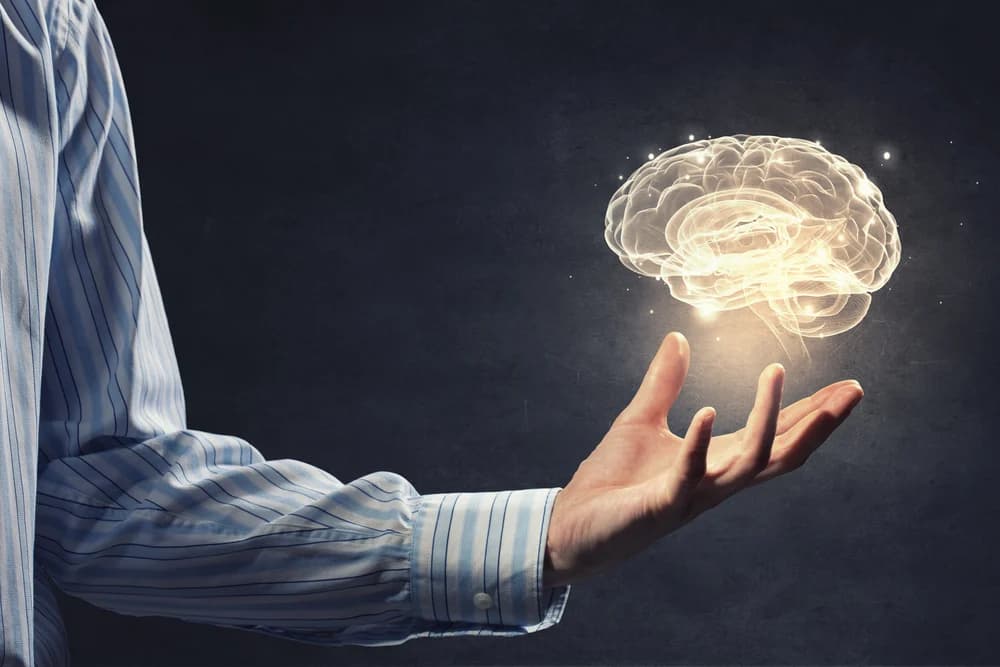 Man holding a levitating brain which is glowing golden yellow