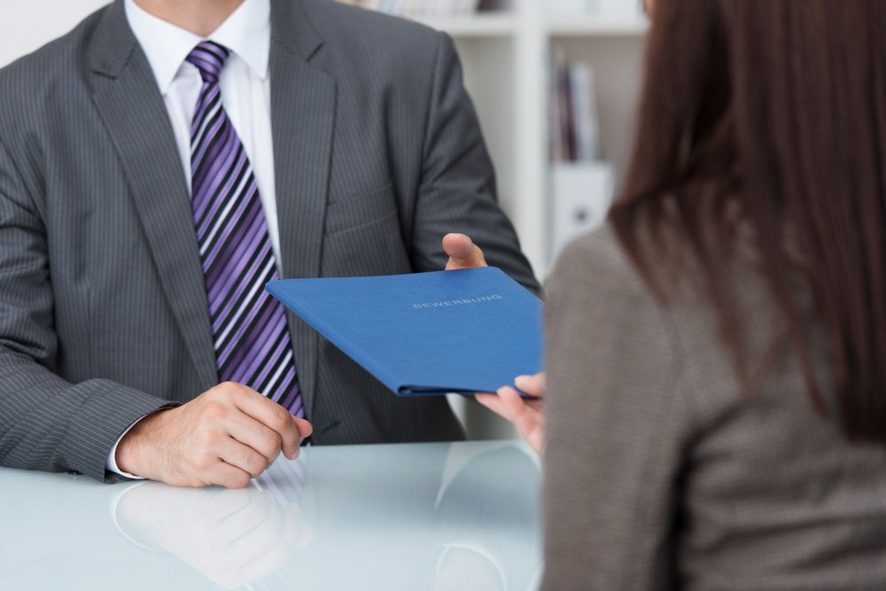 Man handing a handbook over to a female colleague across a desk