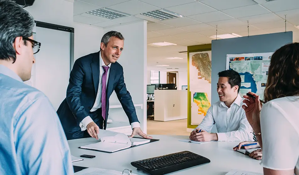 Executive talking to 3 employees over a desk