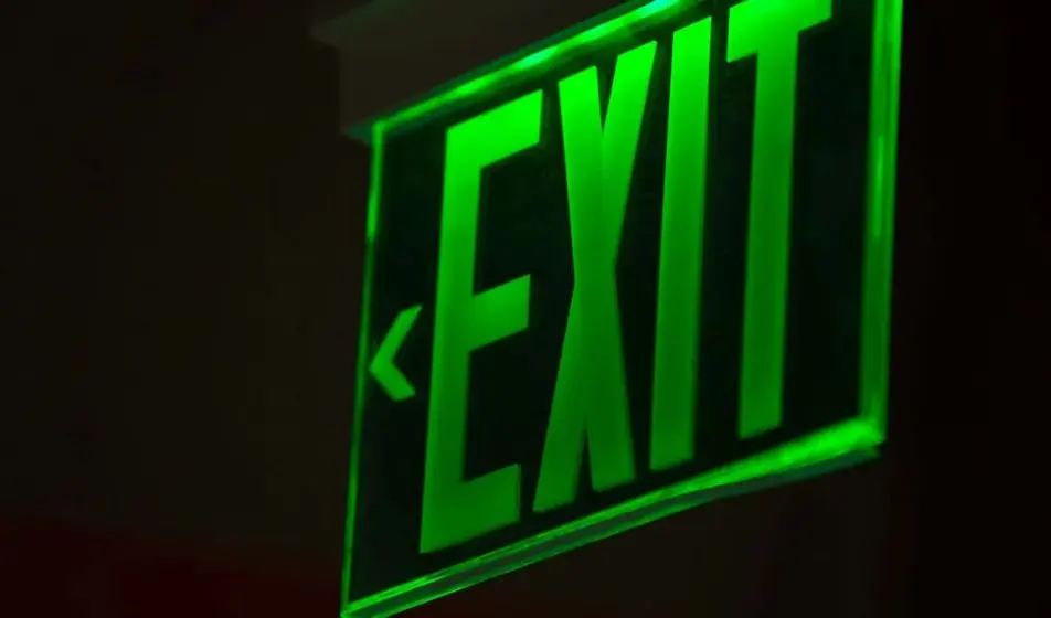 A green exit sign lighting up a dark room.