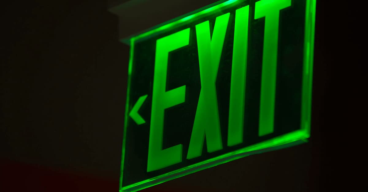 A green exit sign lighting up a dark room.