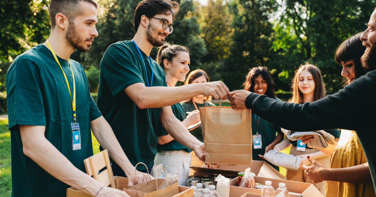 Volunteers at an outdoor food bank handing out supplies, illustrating health and safety in charities and voluntary organisations.