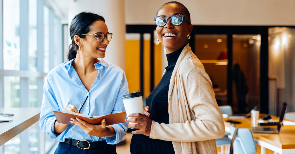 Two colleagues talking in an office, illustrating the importance of maternity risk assessments in supporting pregnant employees at work.