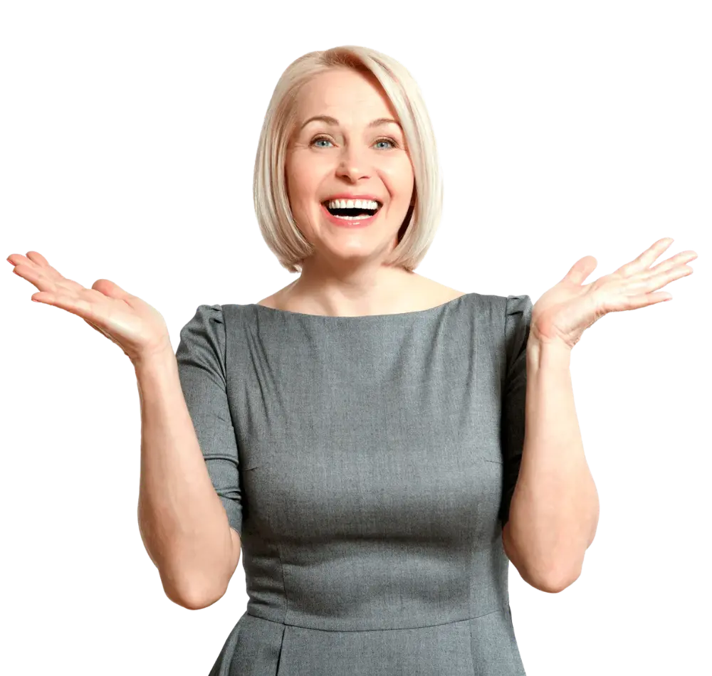 lady with short blonde hair in a smart grey dress smiling, looking happily at the camera with her hands in a shrug position