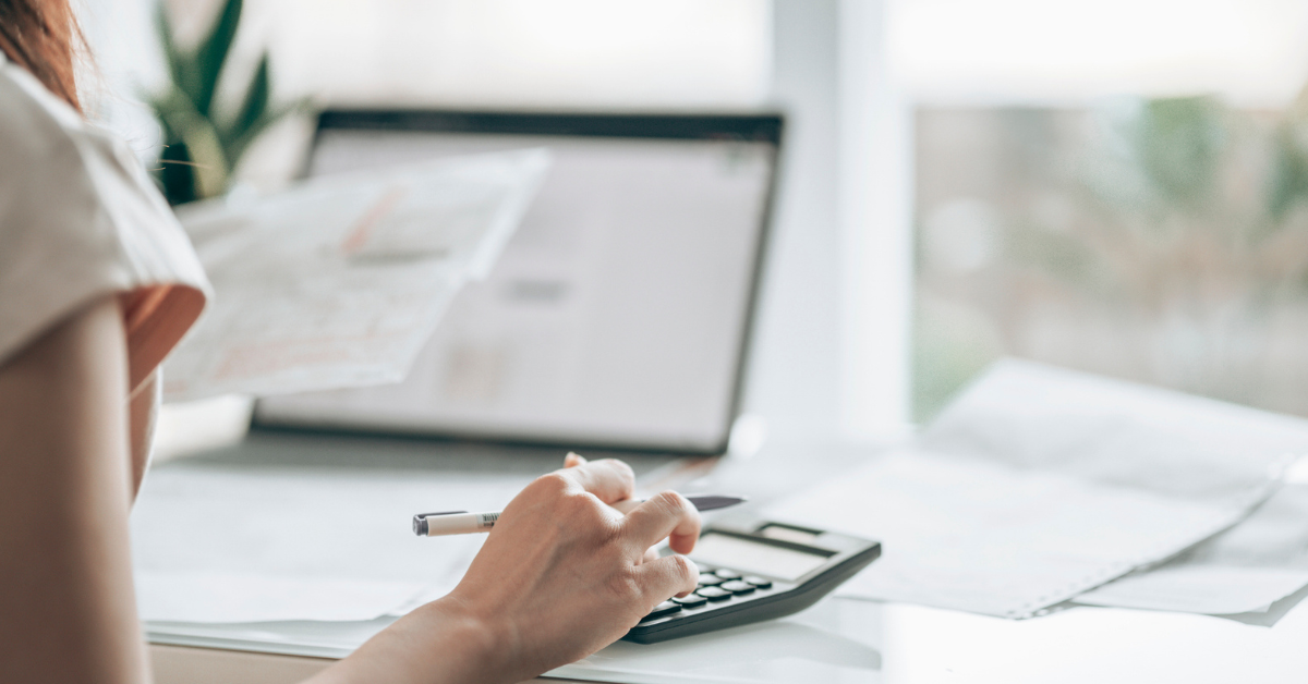 Woman using a calculator to work out redundancy pay entitlement while preparing for the process of making staff redundant.
