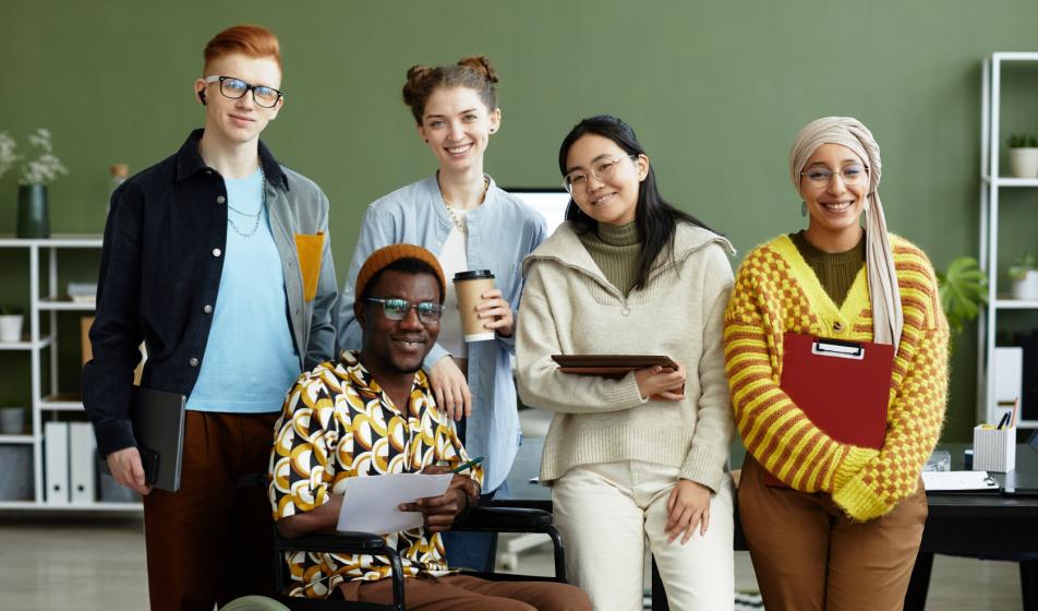 Group of multi ethnic young people sitting against a table smiling