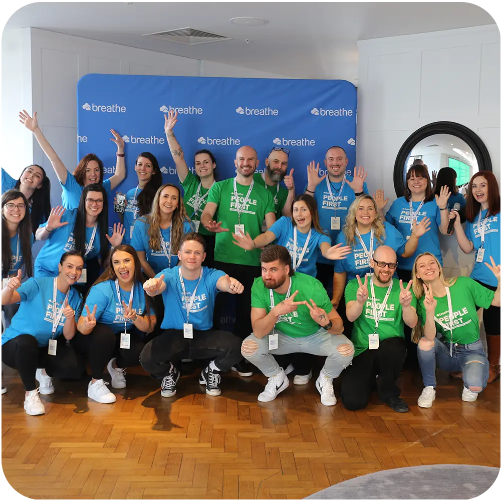 Team Breathe wearing bright green and blue tshirts standing in front of a Breathe banner at the event