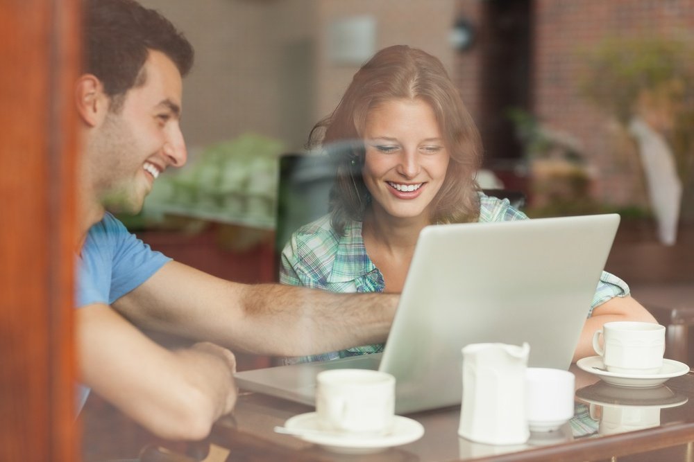 Two laughing students looking at a laptop