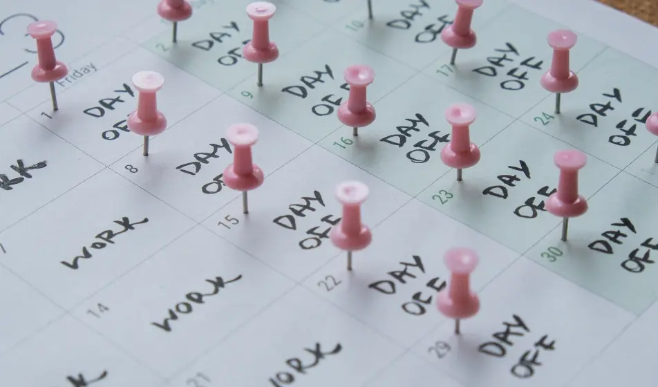 Calendar with work days and days off written in each day - days off have pins in too