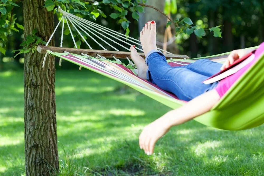 Young lady resting in a hammock with a book