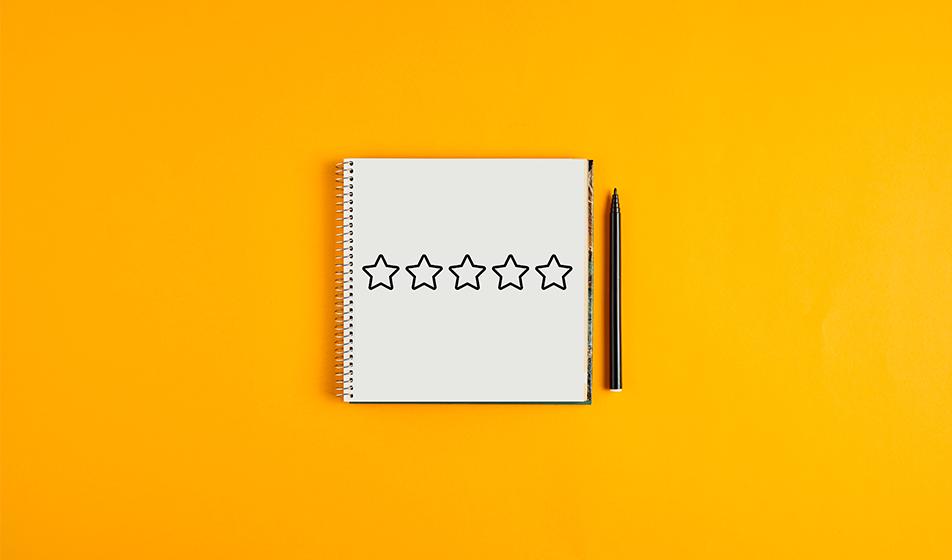 A notebook with 5 stars on it is shown next to a pen against a tangerine orange background