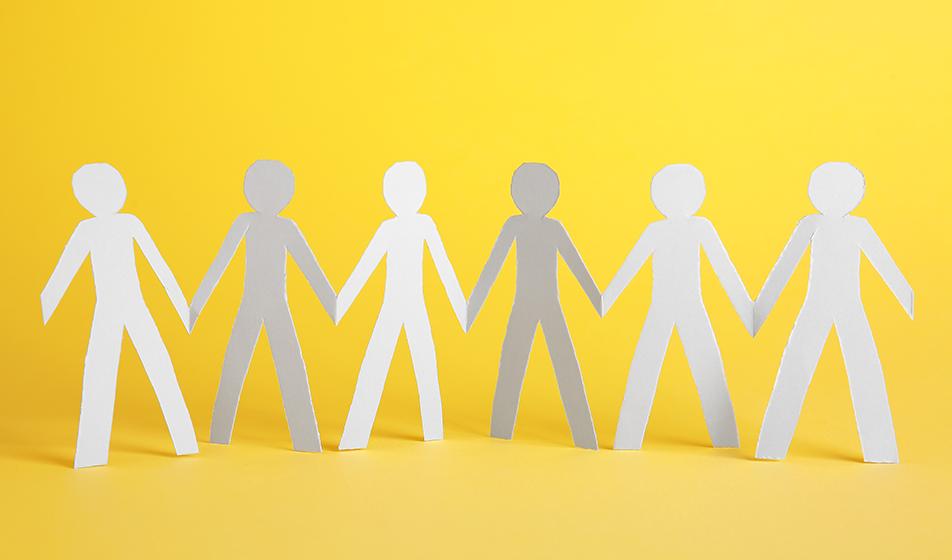 A paper chain of people are shown, cut out of white paper, standing against a yellow background