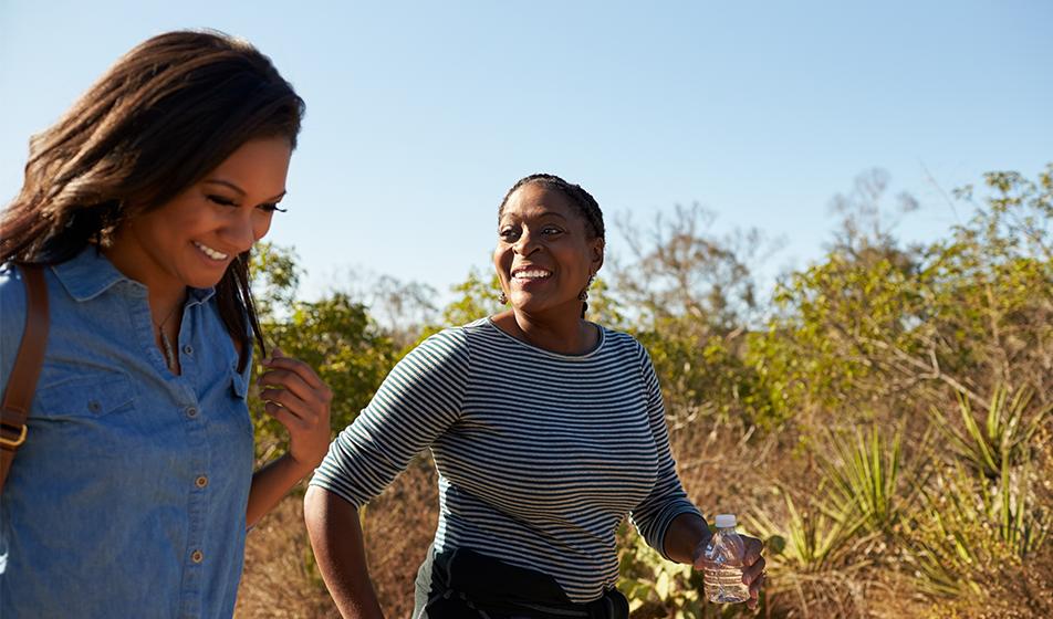 Two women are walking outside. They look happy and are smiling. 