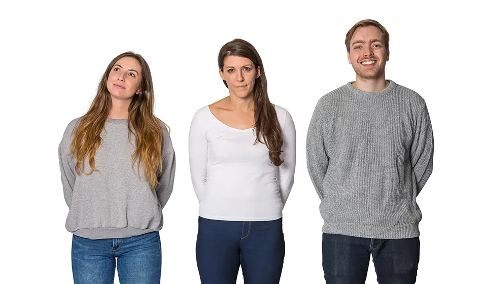 Three team members standing together. Two are looking towards the camera and one is looking upwards.