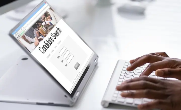 Someone types on a keyboard, where 'candidate search' is shown on their screen