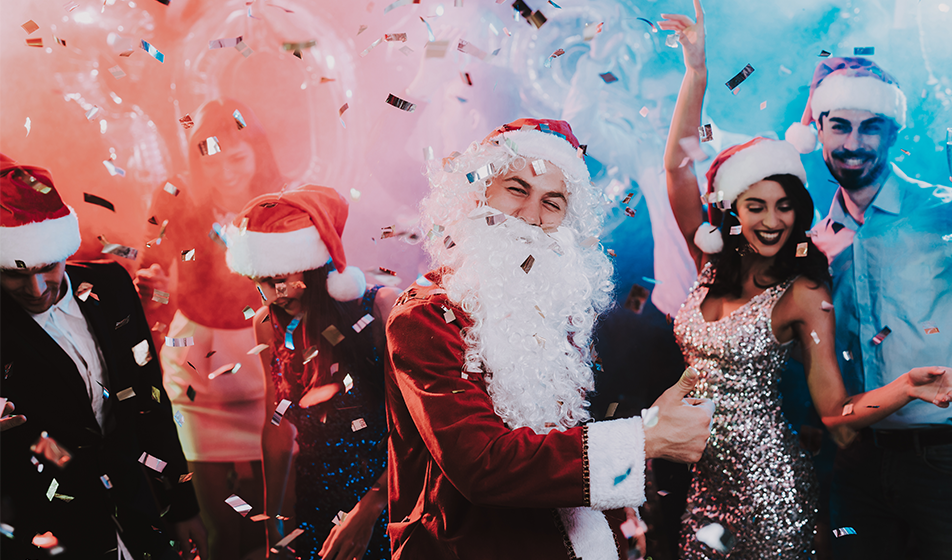 People dancing around someone dressed up as Santa Clause, with confetti and bright lights