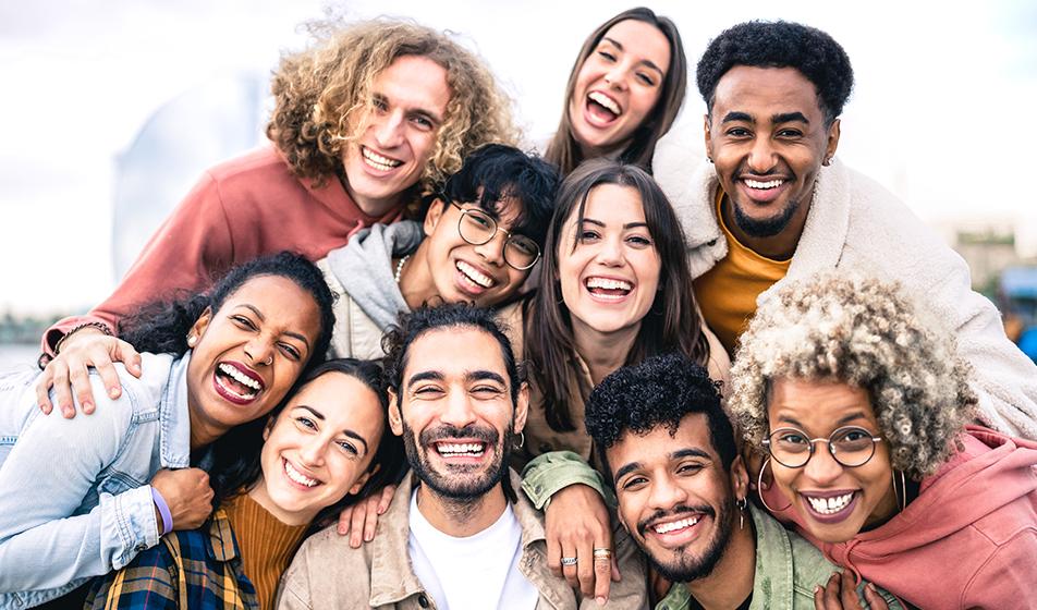 A group of diverse smiling people huddle together in a happy group 