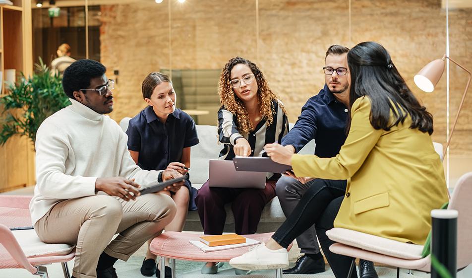 A group of employees sit around a coffee table. They look like they're having a comfortable, relaxed work discussion