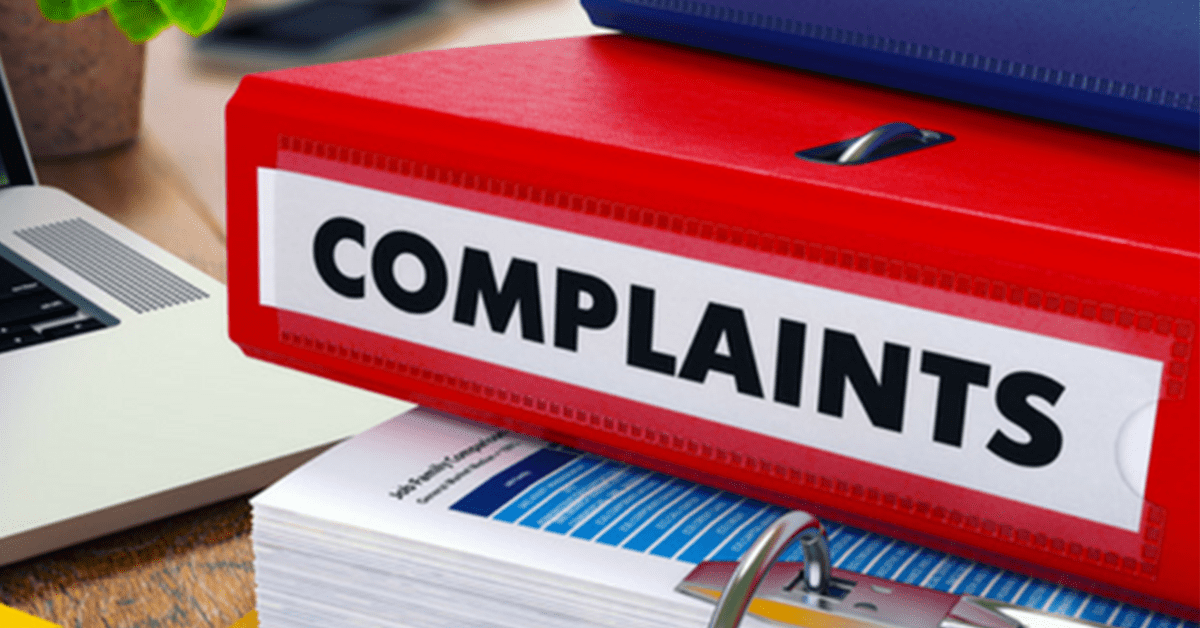 A large red folder is sat between two other folders. On the side of the red folder in large black letters is the word "complaints". This is the folder that is used to log workplace grievances.
