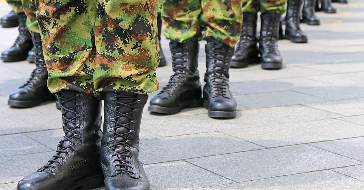 Several soldiers stood in a formation. They have black laced boots on with army camouflage trousers.